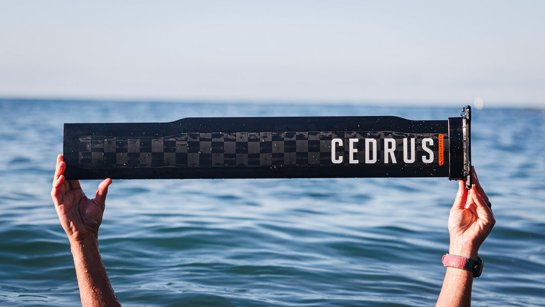 Someone submerged in the ocean where only his hands holding a Cedrus mast are visible above the water. Demonstrating its hollow architecture and lightweight design that doesn’t compromise on strength while also being good for the environment