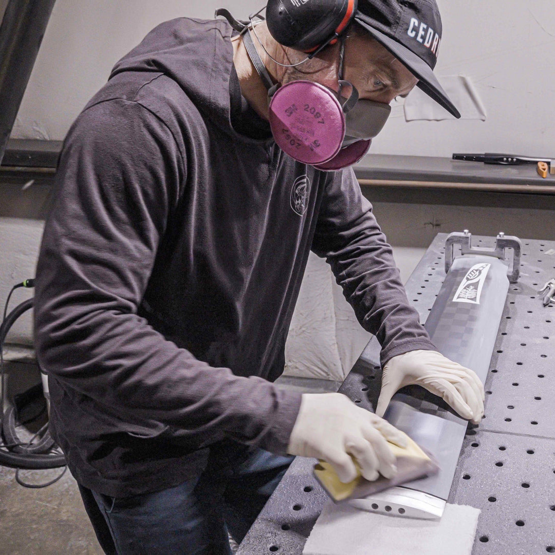 Person wearing protective gear working on a metal surface in a workshop.