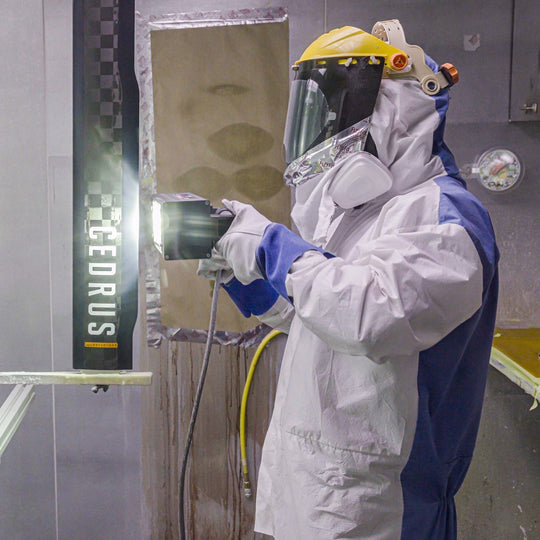Person in protective suit and mask using a machine with 'CEDRUS' branding in a laboratory setting.