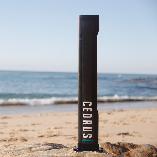 The Cedrus Evolution Surf Mast rests against a scenic overlook, suggesting the endless possibilities it offers to riders seeking to push their limits and experience the pinnacle of foiling performance.